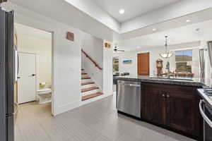 Kitchen featuring stainless steel appliances, a sink, dark brown cabinets, ceiling fan, and decorative light fixtures