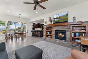 Living room with ceiling fan, a stone fireplace, baseboards, and recessed lighting