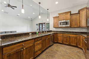 Kitchen with stainless steel appliances, a sink, dark tile patterned floors, pendant lighting, and ceiling fan