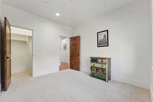 Unfurnished bedroom with carpet flooring, baseboards, a walk in closet, recessed lighting, and a closet