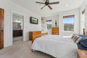 Bedroom featuring light carpet, recessed lighting, ensuite bath, ceiling fan, and baseboards