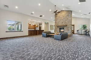 Living room featuring carpet floors, ceiling fan, high vaulted ceiling, a fireplace, and baseboards