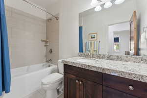 Full bath featuring toilet, vanity, shower / bathtub combination with curtain, and tile patterned flooring