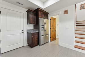 Kitchen with stainless steel refrigerator with ice dispenser and dark brown cabinets