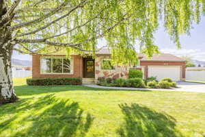 View of front of house with a garage, driveway, and brick siding