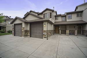 View of front of property featuring concrete driveway, an attached garage, stone siding, and roof with shingles