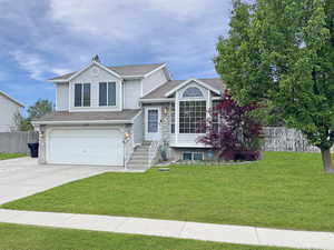 Tasteful exterior of home featuring a 2 car garage and beautiful landscape and mature trees