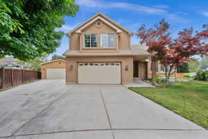 Traditional home featuring a garage, a shingled roof, brick siding, driveway, and stucco siding