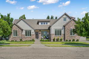 Craftsman house with board and batten siding, stone siding, a shingled roof, and a front yard