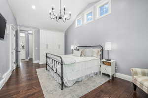 Bedroom with dark wood finished floors, high vaulted ceiling, and a chandelier
