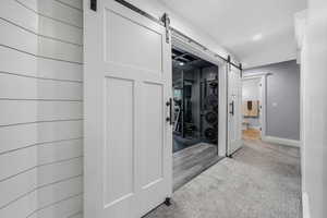 Hallway with a barn door, carpet flooring, and recessed lighting
