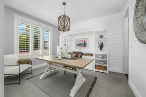 Home office with carpet flooring and wooden walls