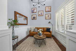 Sitting room with wood finished floors, a chandelier, wainscoting, and a decorative wall