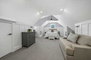 Bedroom featuring light carpet, a decorative wall, vaulted ceiling, and ceiling fan