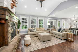 Living area with vaulted ceiling, a fireplace, ceiling fan, hardwood / wood-style floors, and recessed lighting