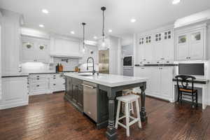 Kitchen featuring dishwasher, white cabinetry, decorative backsplash, dark wood finished floors, and recessed lighting
