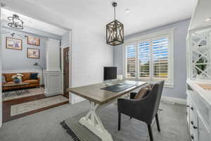 Office area featuring light carpet and a chandelier
