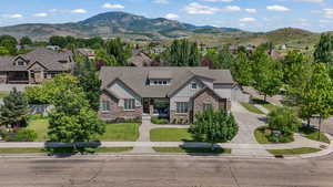 View of front of house featuring board and batten siding, concrete driveway, stone siding, a mountain view, and a residential view