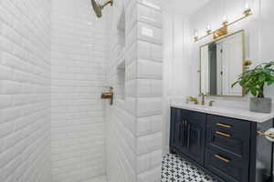 Full bath featuring tiled shower and vanity