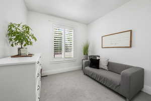 Living area with baseboards and light carpet