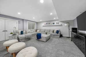 Living room with carpet flooring, recessed lighting, and wooden walls