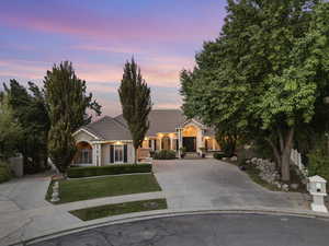 View of front of property with concrete driveway, a front lawn, a tiled roof, and stucco siding