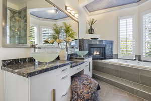 Full bathroom featuring a tile fireplace, tile patterned flooring, a garden tub, and double vanity