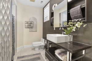 Bathroom featuring toilet, tile patterned floors, baseboards, and vanity
