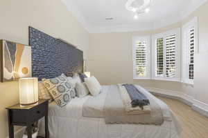 Bedroom with crown molding, wood finished floors, and baseboards