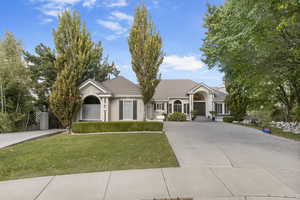 Ranch-style house with concrete driveway, a tiled roof, a front lawn, and stucco siding
