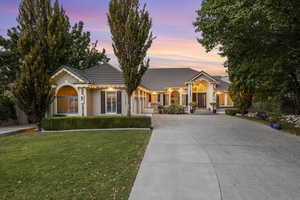 View of front of home featuring concrete driveway, a tile roof, a yard, and stucco siding