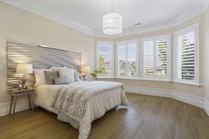 Bedroom with crown molding, multiple windows, light wood-style floors, and baseboards