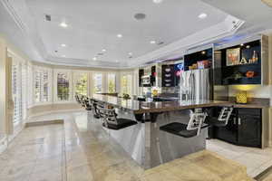 Bar area featuring a tray ceiling, stainless steel fridge, recessed lighting, light tile patterned floors, and a sink