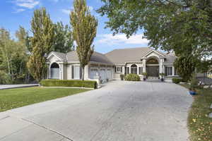 Single story home featuring a garage, a front lawn, driveway, a tile roof, and stucco siding