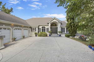 View of front of property featuring a tile roof, concrete driveway, an attached garage, and stucco siding
