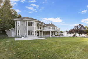 Back of property with a lawn, a balcony, a patio, and stucco siding