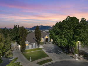 View of front of house featuring a tiled roof, driveway, a mountain view, a lawn, and stucco siding