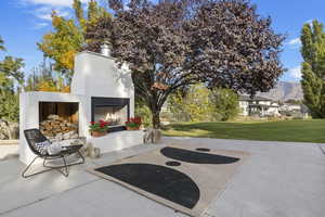 View of patio / terrace featuring a warm lit fireplace and a mountain view
