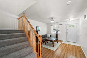 Living room with light wood-style floors, stairs, a textured ceiling, and baseboards