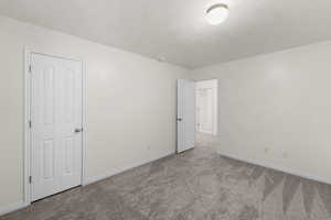Unfurnished bedroom featuring carpet flooring, baseboards, and a textured ceiling