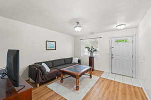 Living area featuring light wood finished floors, a textured ceiling, and baseboards