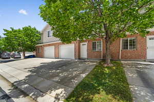 Obstructed view of property featuring driveway, a garage, and brick siding