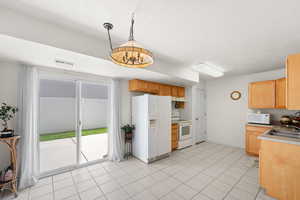 Kitchen featuring white appliances, a sink, under cabinet range hood, a textured ceiling, and light brown cabinetry