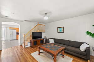 Living area featuring arched walkways, light wood-style flooring, stairs, and baseboards