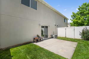 Rear view of house with central air condition unit, a gate, a patio area, and stucco siding