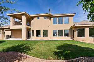 Rear view of house with a balcony, stucco siding, a lawn, a patio, and central air condition unit