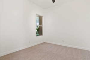 Spare room with light colored carpet, baseboards, and a ceiling fan