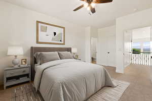 Carpeted bedroom featuring ensuite bath, baseboards, and a ceiling fan
