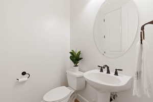 Bathroom with toilet, baseboards, and a sink
