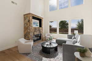Living room featuring a fireplace, wood finished floors, baseboards, and a towering ceiling